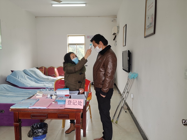 图为璜泾镇残疾人志愿者王丽倩在为外来人员测体温